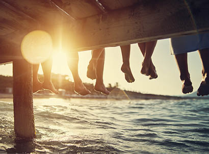 Five people having fun sitting on pier. Feet shot from below the pier. Sunny summer day evening. Nikon D850