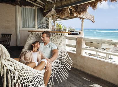 A beautiful young couple smiling at each other on a hammock.