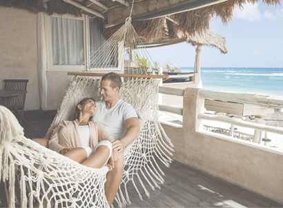 A beautiful young couple smiling at each other on a hammock.