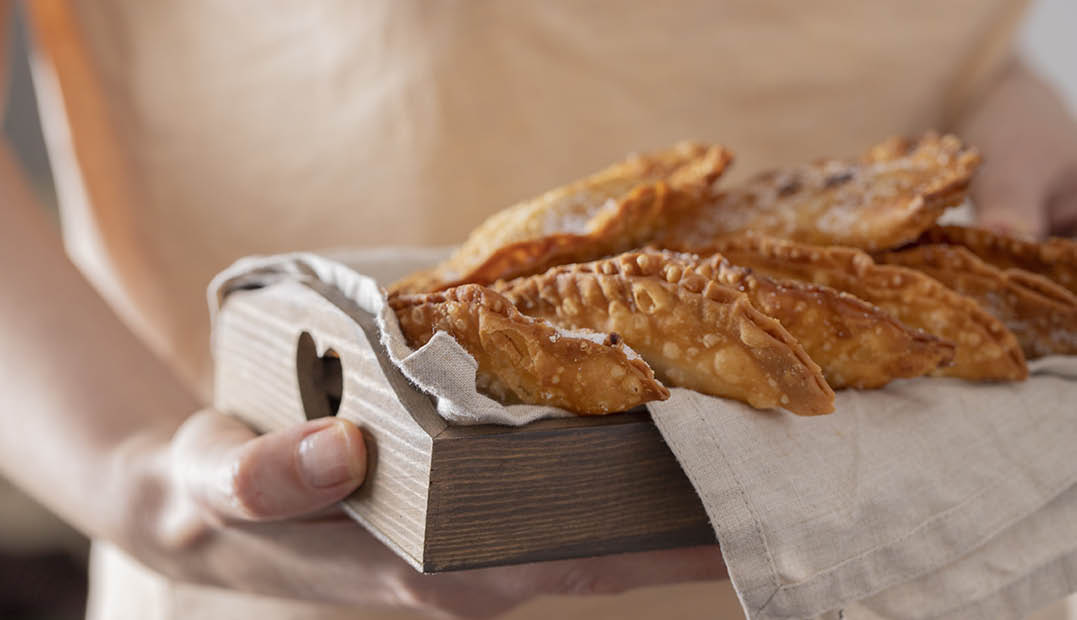 Female hand holding wooden try with Trucha, typical sweet consumed in Canary Islands during the Christmas time.