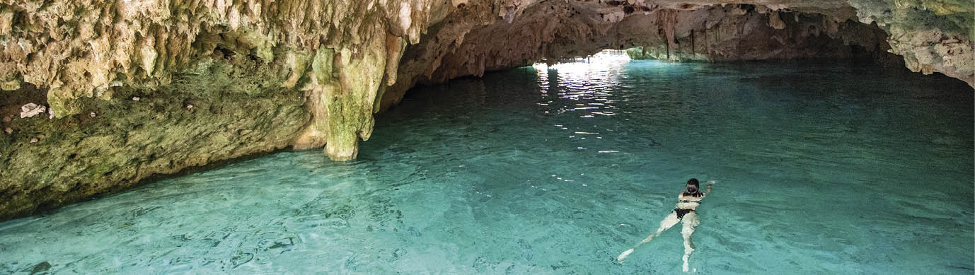Woman swimming in freshwater Cenote in Cancun Mexico 