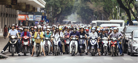 Motorcycles got traffic jam on the road with green trees in background at Hanoi, Vietnam.