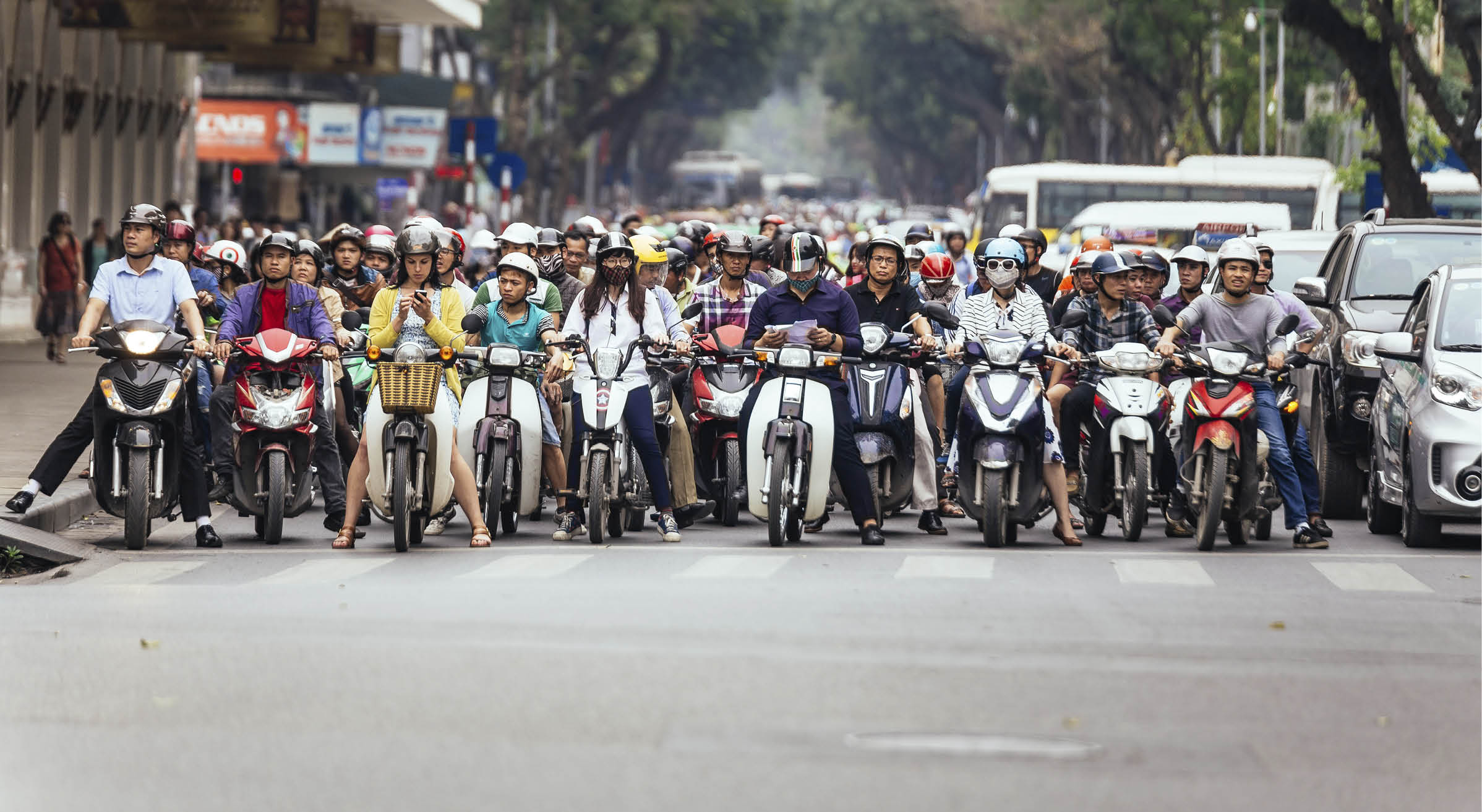 Motorcycles got traffic jam on the road with green trees in background at Hanoi, Vietnam.