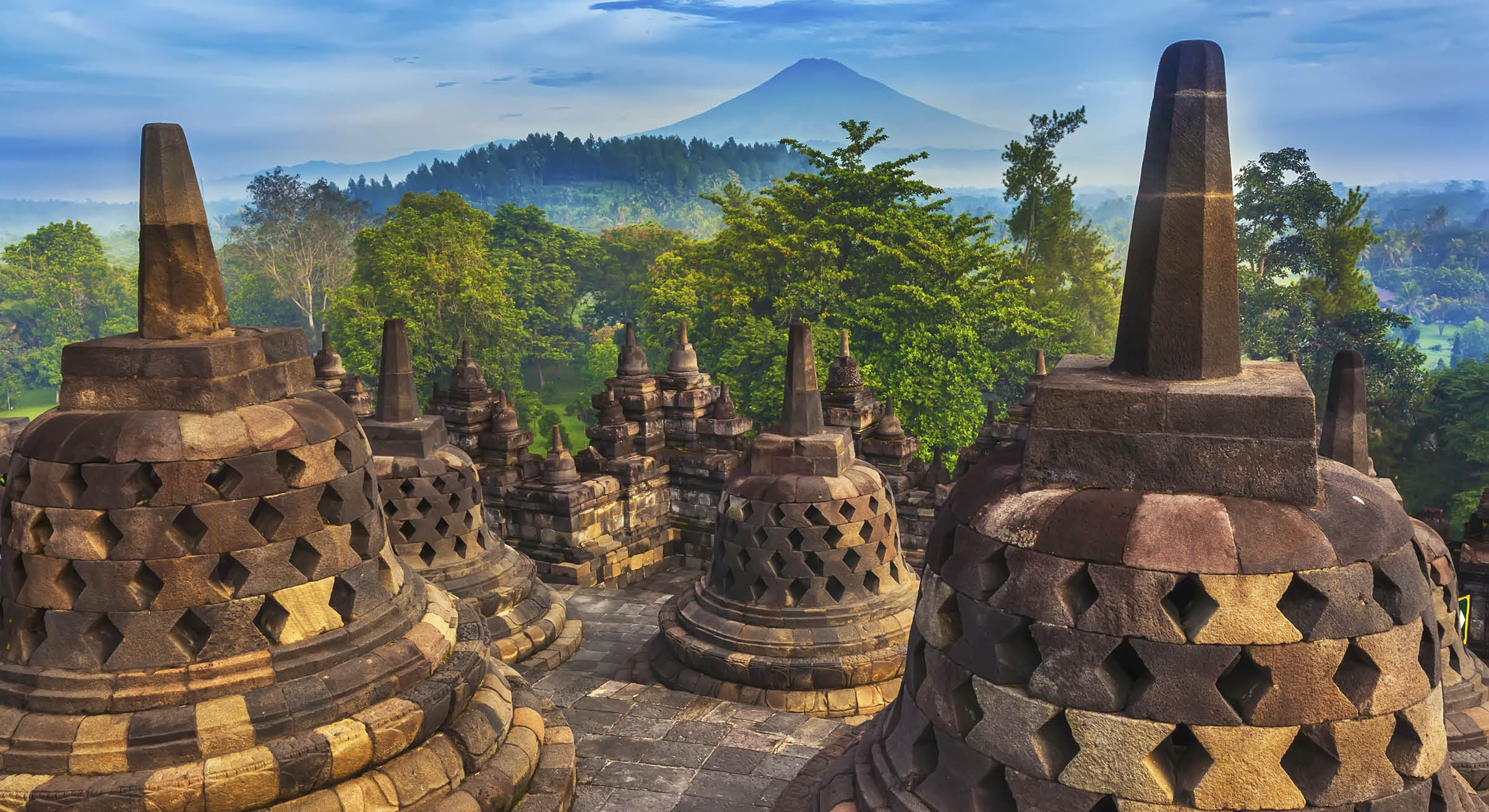 Candi Borobudur in the background of rainforest, morning mist and Sumbing Mountain.