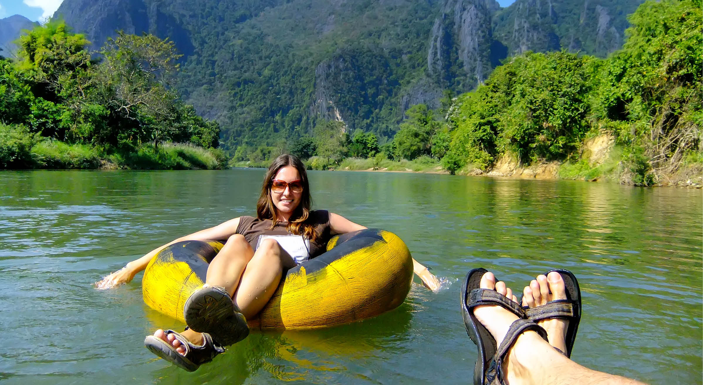 Couple going down Nam Song River in a tube surrounded by karst scenery in Vang Vieng, Laos. Tubing is a popular tourist activity in Vang Vieng.