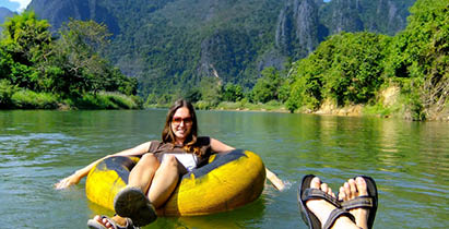 Couple going down Nam Song River in a tube surrounded by karst scenery in Vang Vieng, Laos. Tubing is a popular tourist activity in Vang Vieng.