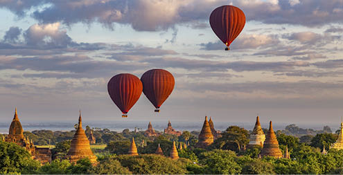 3 Red Hot Air Balloons above colorful ancient temples at Sunrise in Bagan, Myanmar