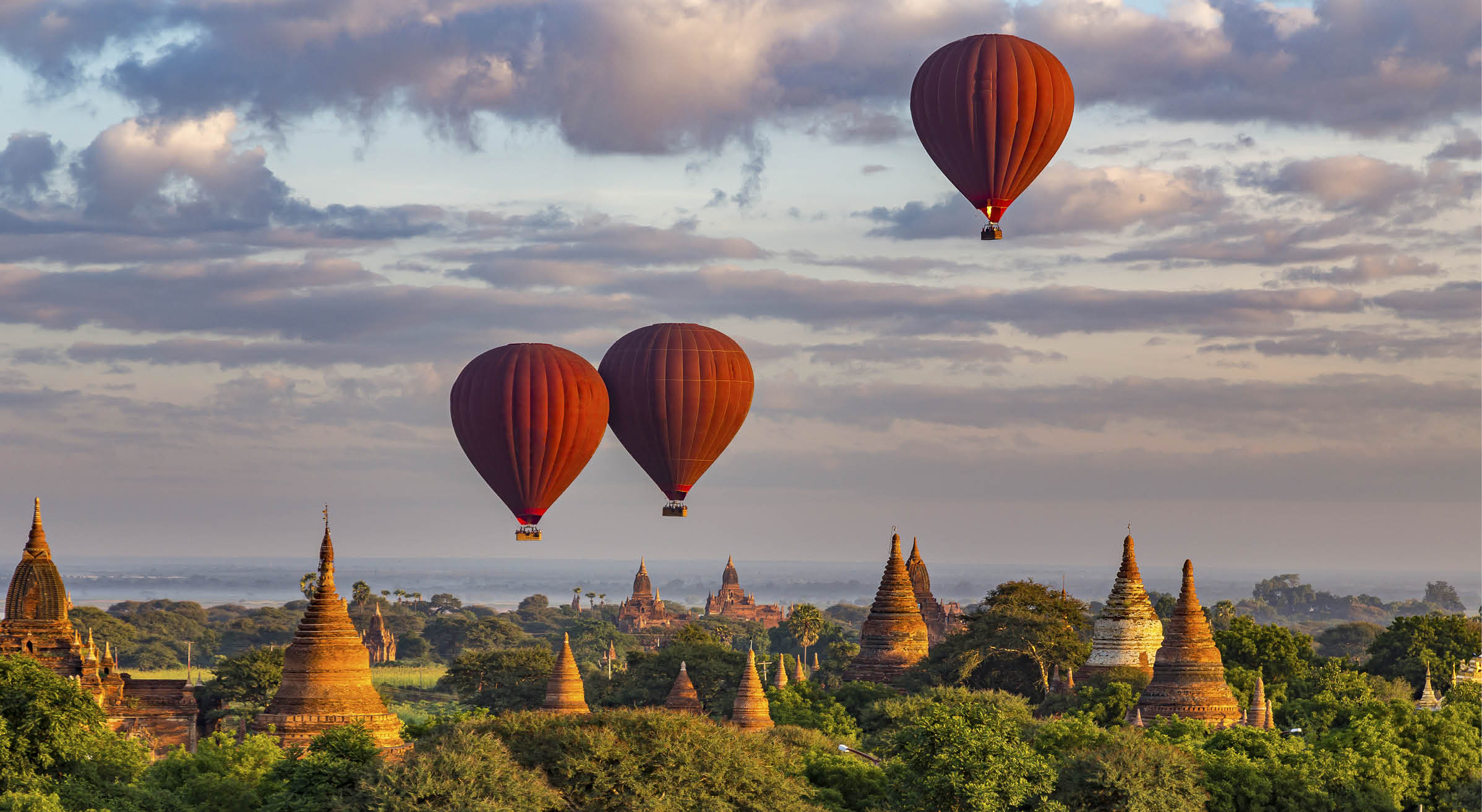 3 Red Hot Air Balloons above colorful ancient temples at Sunrise in Bagan, Myanmar