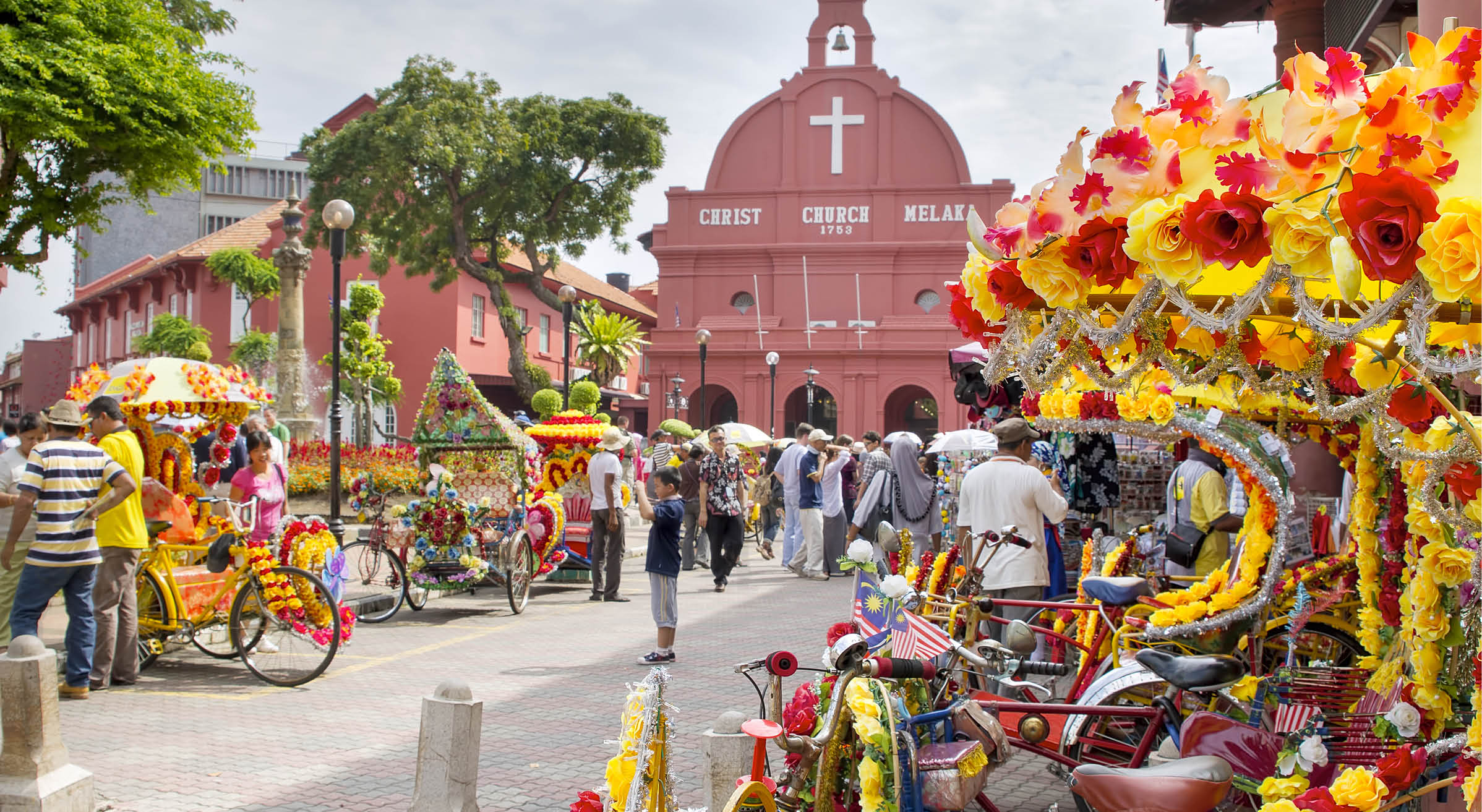 MELAKA, MALAYSIA - JAN 14 : Christ Church Melaka on Jan 14, 2012 in Melaka Malaysia. A popular historic tourist attraction in Melaka Malaysia with flower decorated tricycles for hire.