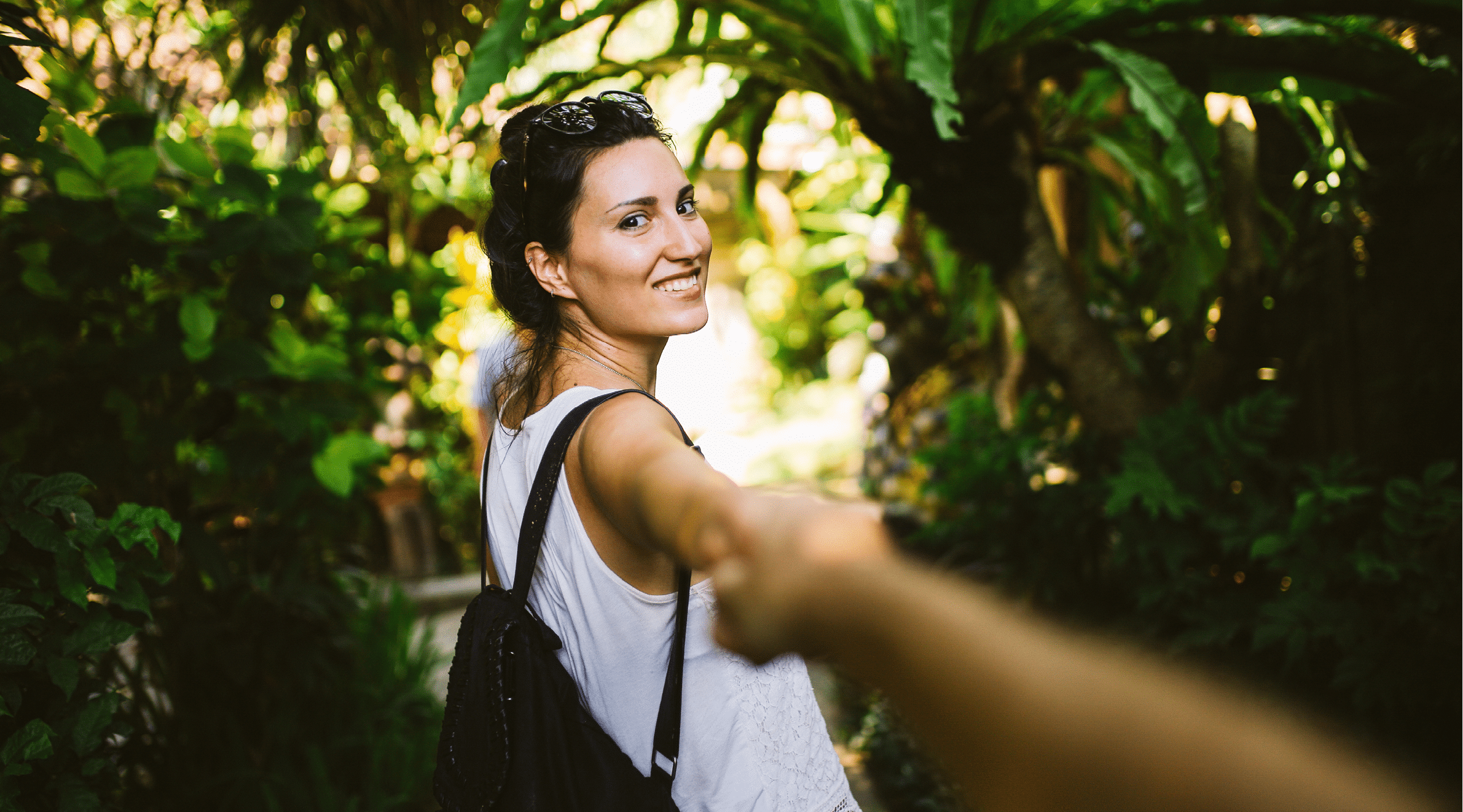 Image of a young couple walking through the tropical forest in Bali, Indonesia  She is carrying a backpack, and wearing casual yoga summertime clothing, enjoying her time on the beautiful island in the Southeast Asia 