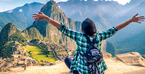 A woman tourist contemplating the amazing landscape of Machu Picchu with arms open  Archaeological site, UNESCO World Heritage