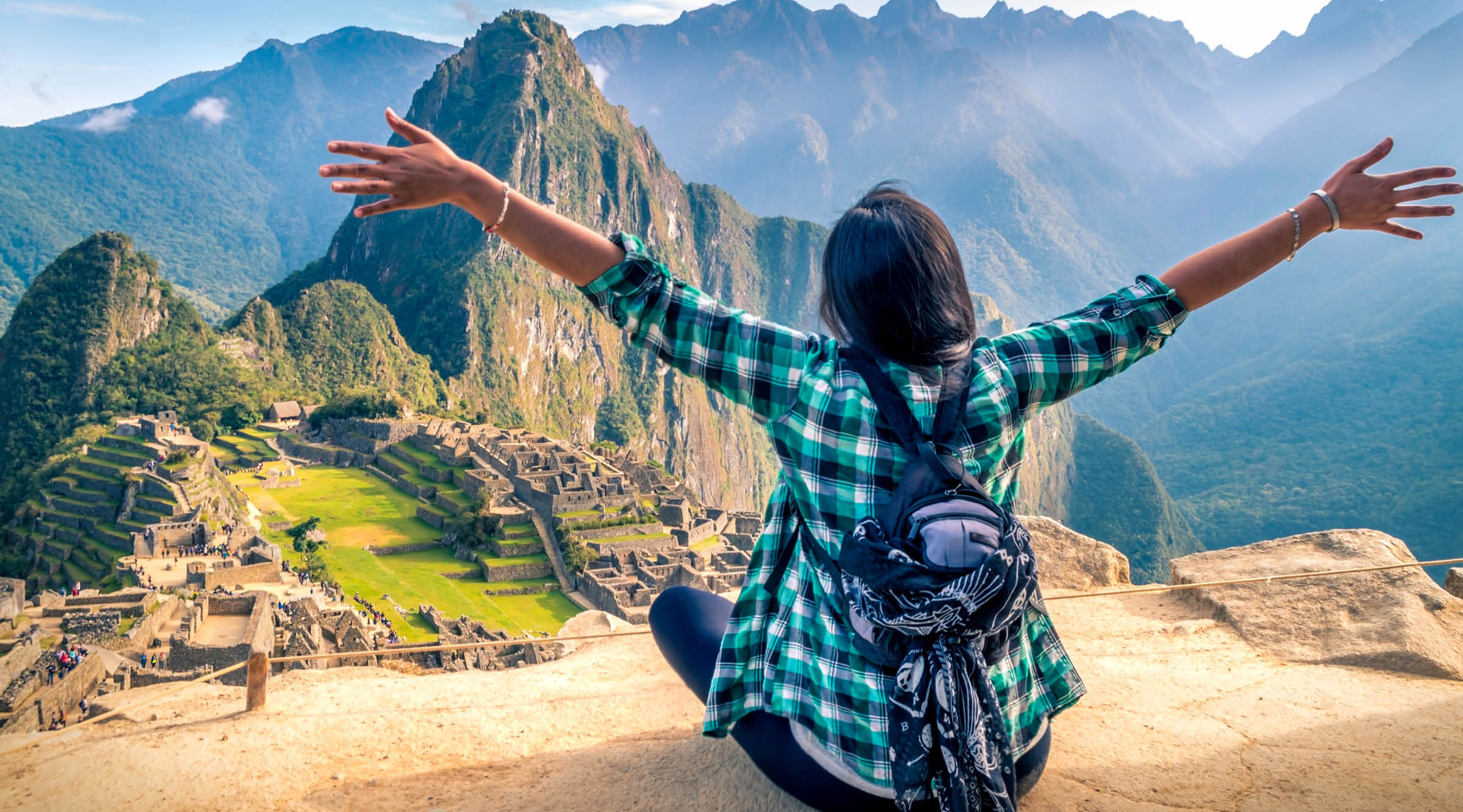 A woman tourist contemplating the amazing landscape of Machu Picchu with arms open  Archaeological site, UNESCO World Heritage