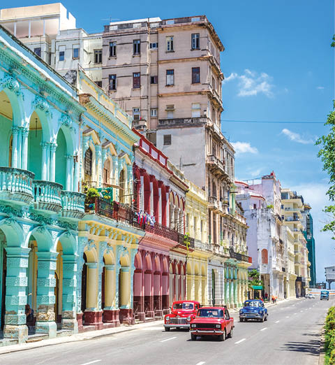 Old american classic cars on street of Havana against multicolored historic buildings