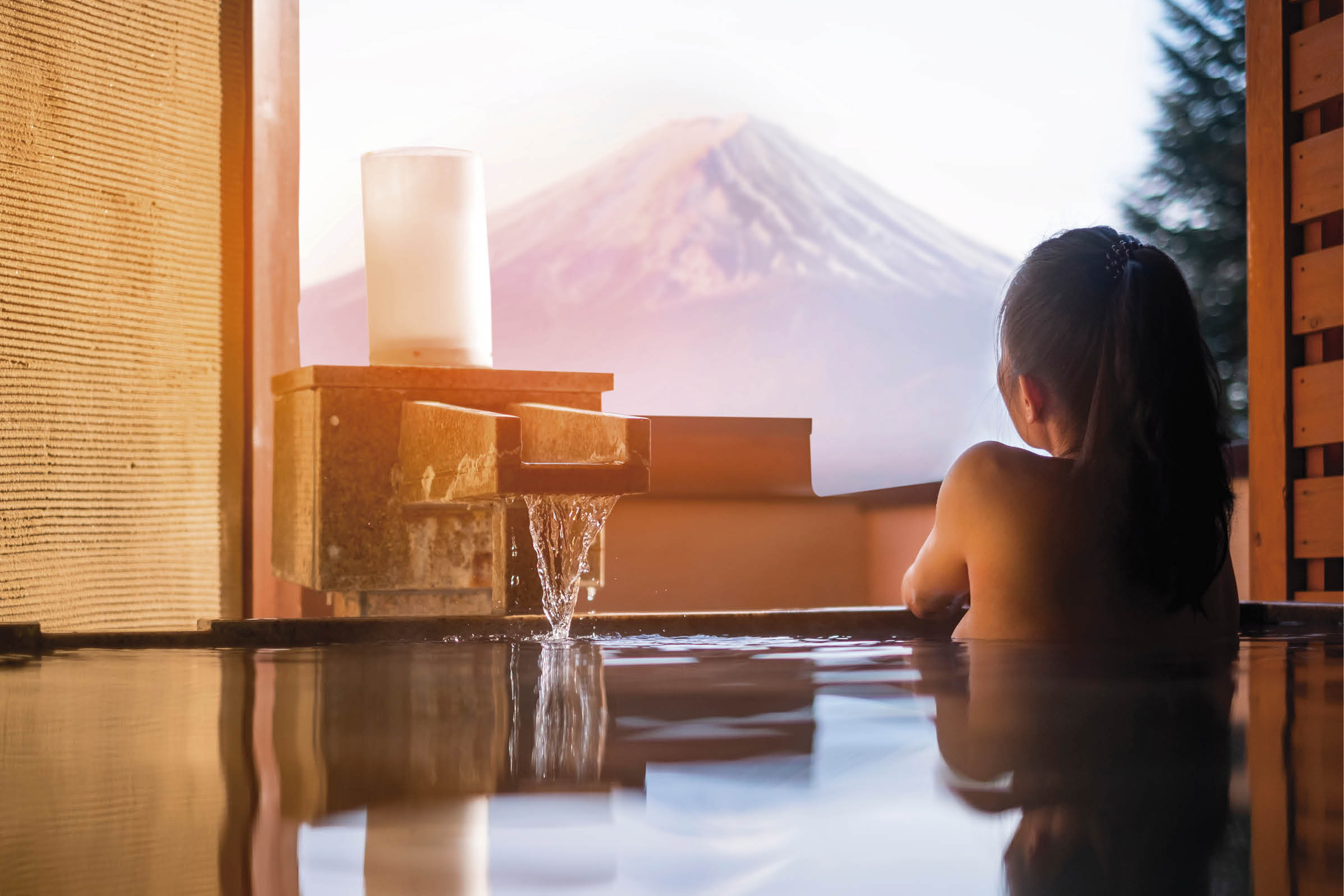 Beautiful woman enjoy onsen (mineral hot bath) in morning and seeing view of Fuji mountain in japan 