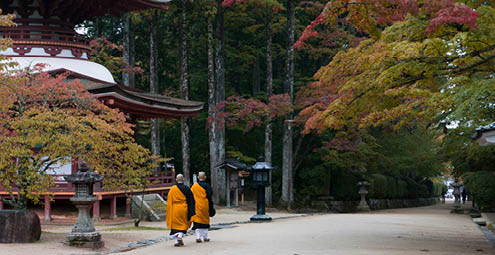 Buddhist monks walking past temple in Koyasan, Mt Koya, Japan during autumn. 
