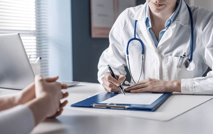 Doctor sitting at desk and writing a prescription for her patient