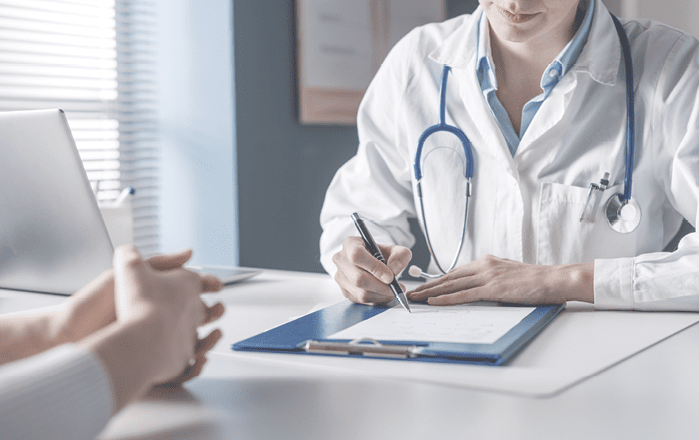 Doctor sitting at desk and writing a prescription for her patient