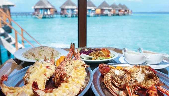 Two plates with lobster on table at window with view on ocean