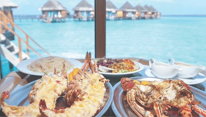 Two plates with lobster on table at window with view on ocean