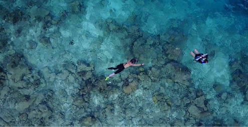 An aerial view of a man diving on the sea in Rasdhoo Island in the Maldives