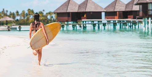 Beautiful surfer woman ready to surfing in turquoise sea, on stand up paddle board at exotic vacation