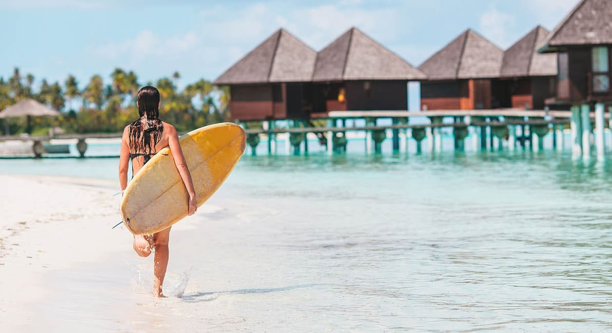 Beautiful surfer woman ready to surfing in turquoise sea, on stand up paddle board at exotic vacation