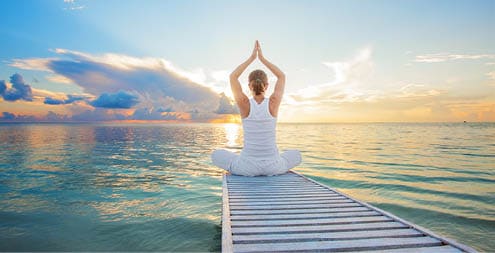 Caucasian woman practicing yoga at seashore