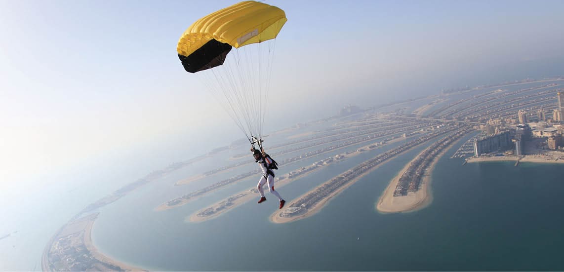 Dubai dream.Yellow extreme skydiving activity fun people on Dubai palm Jumeirah. Skydive Dubai jump travel. Yellow fun parachute jump. Summer outdoor sky activity. Big goal