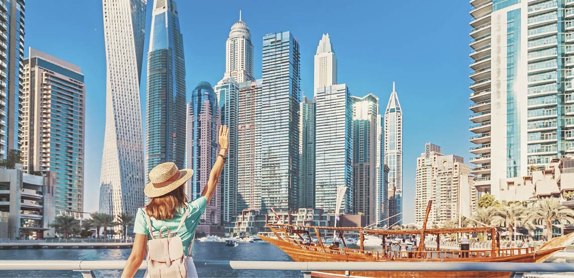 Cheerful asian traveler girl walking on a promenade in Dubai Marina district. Travel destinations and tourist lifestyle in UAE